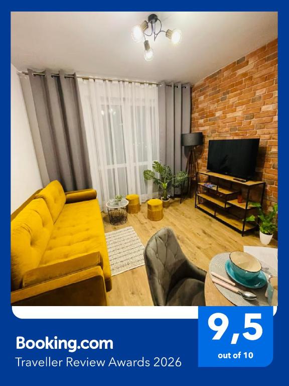 a living room with a yellow couch and a tv at Lotus Apartments Natura parking balcony in Ostrołęka