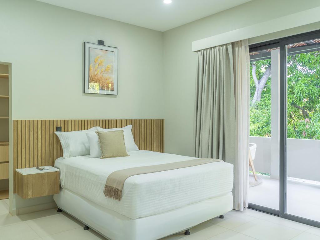 a white bedroom with a bed and a window at Miradora House in El Sunzal