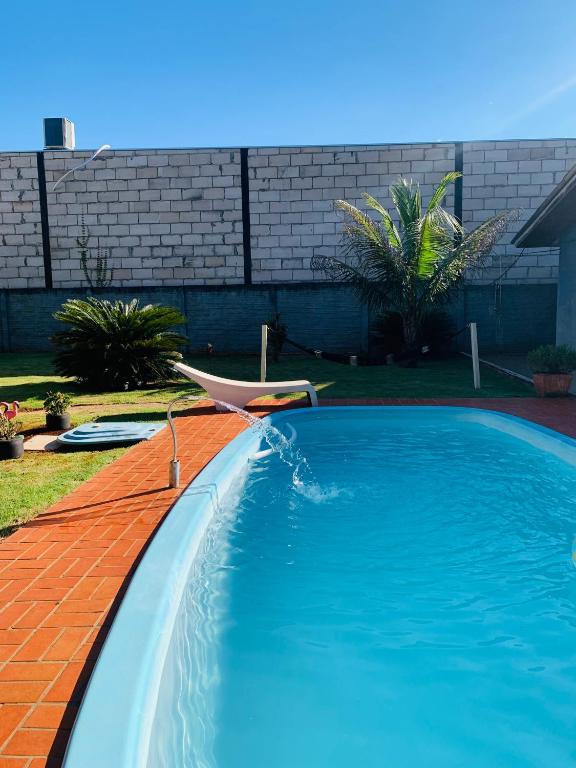 a swimming pool with a chair in a yard at Casa Nina, com Piscina e Brinquedoteca, Super Próxima das Cataratas e Aeroporto in Foz do Iguaçu