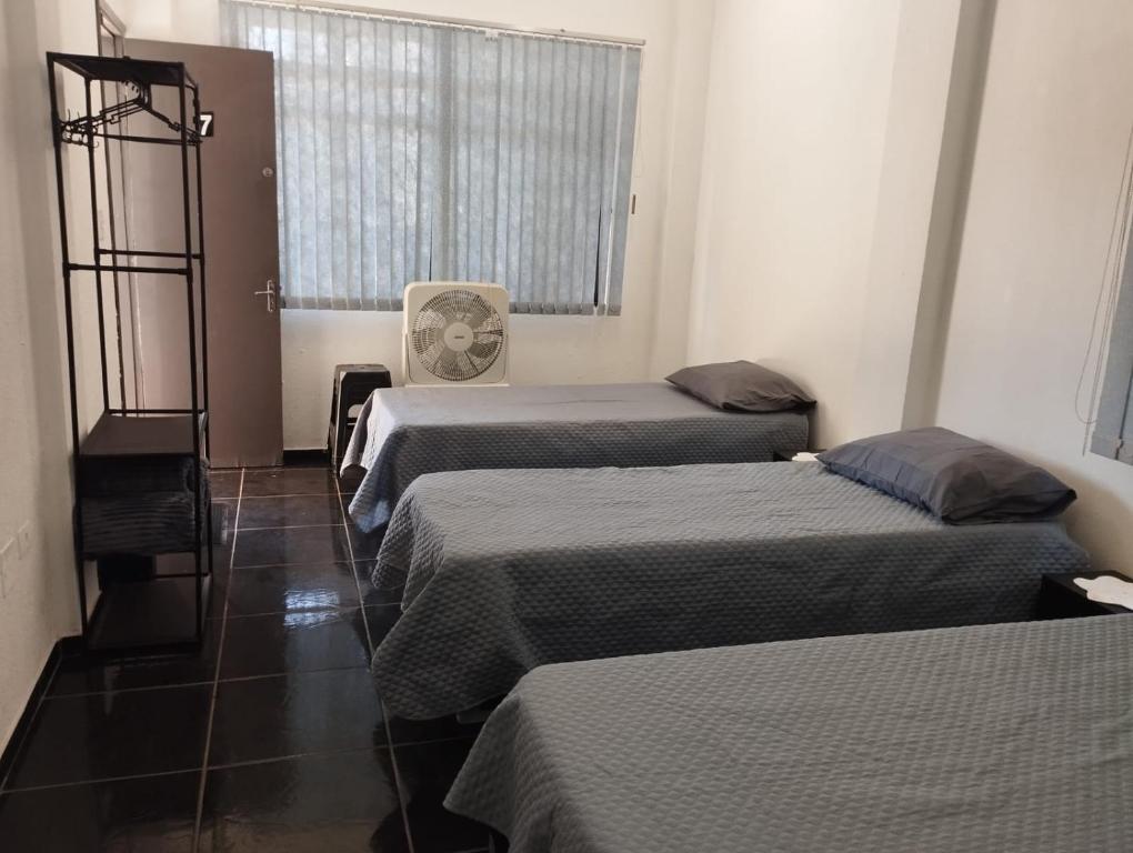 a room with three beds and a window at Espaço Ideal 6 in Cascavel