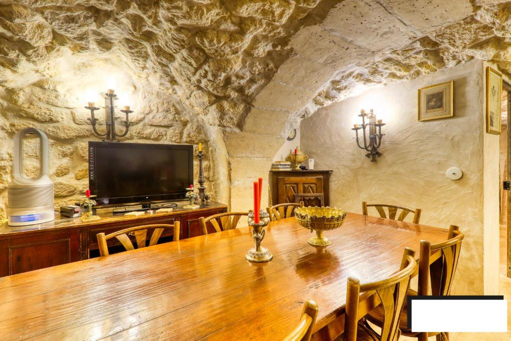 a dining room with a table and a tv at Marais Romantique Paris centre 4 chambres in Paris
