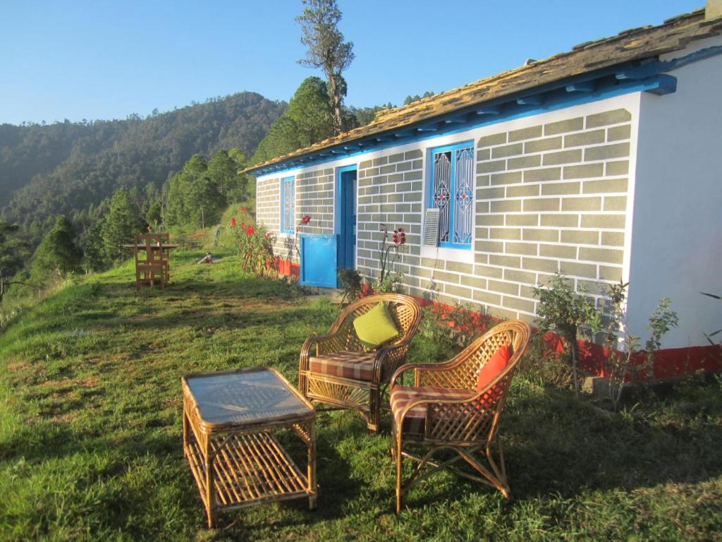 two wicker chairs and a table in front of a house at Thikalna Himalayan Retreat in Almora