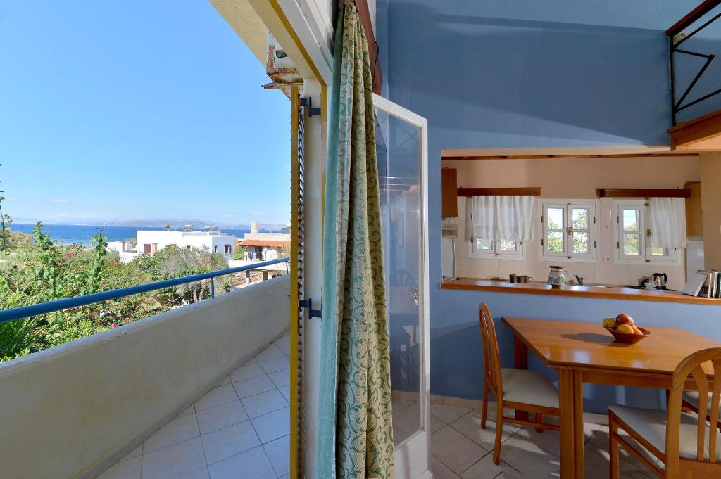 a kitchen and dining room with a table and a balcony at Vagia Beach Apartments, Aegina Island in Vaia
