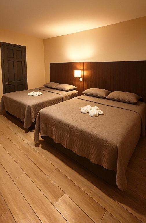 two beds in a hotel room with towels on them at Hotel Boutique 4 Estancias in San Ramón