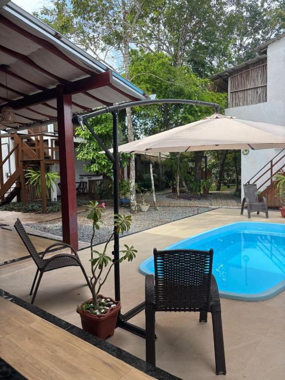 a patio with two chairs and an umbrella and a pool at Villa Sairé in Alter do Chao