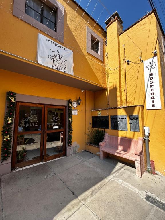 ein gelbes Gebäude mit einer Bank davor in der Unterkunft Casa Ttorrez in San Miguel de Allende