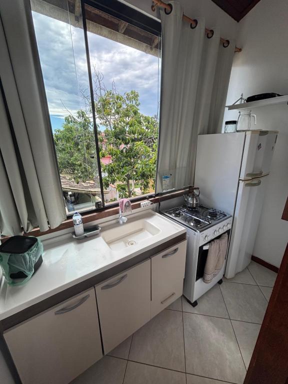 a kitchen with a sink and a refrigerator and a window at Bora Bora Geribá Kitnet in Búzios