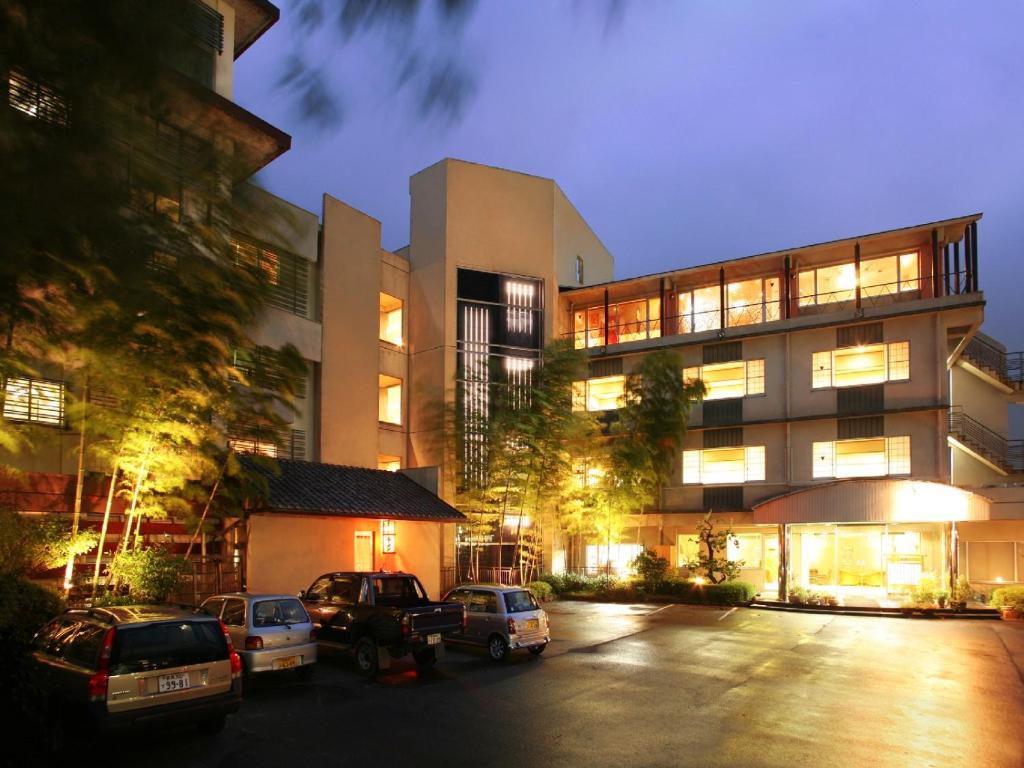a parking lot with cars parked in front of a building at Ryokan Fukuzen in Shibukawa