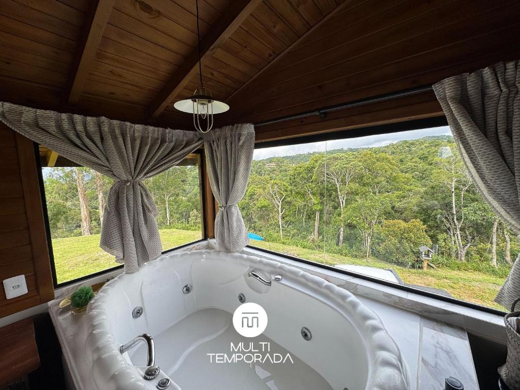 a bath tub in a room with a window at Chalé do Campinho - Rancho Queimado/SC in Rancho Queimado