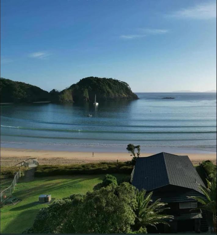 a view of a beach with a house and the ocean at Waetford Road Lodge in Matapouri
