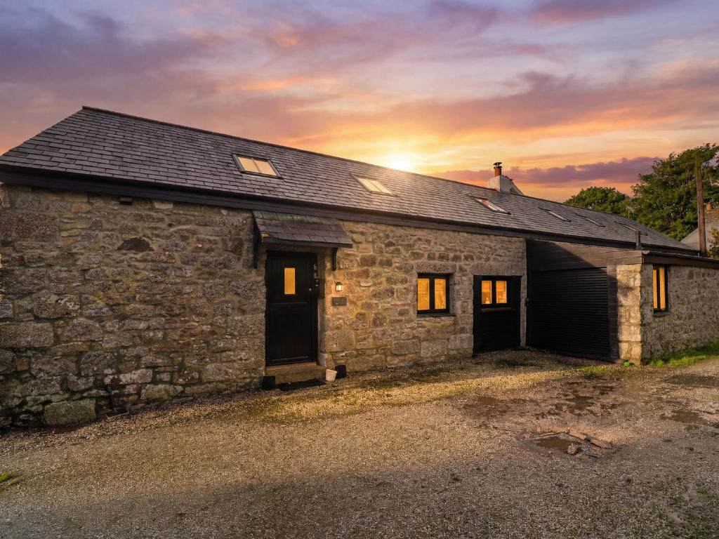 a stone house with the sun setting behind it at Riverside Barn in Truro