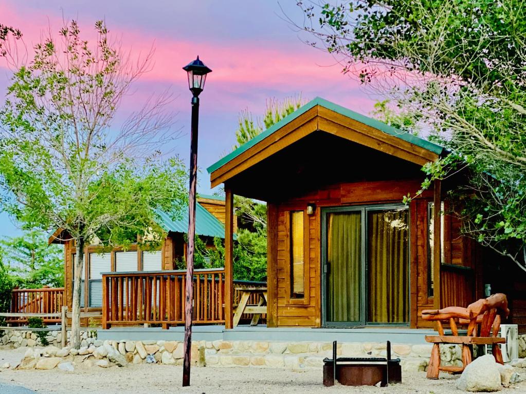 a log cabin with a porch and a street light at Boulder Creek RV Resort in Lone Pine