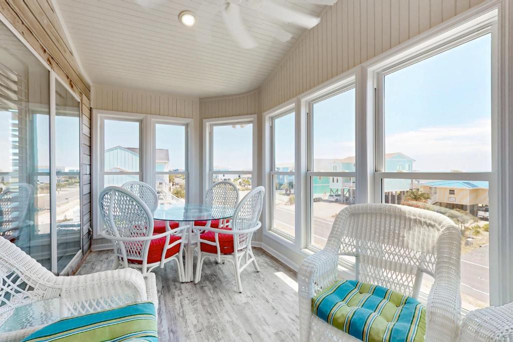 a dining room with a table and chairs and windows at HB303 My Flippin' House in Holden Beach