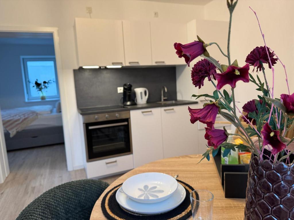 a kitchen with a table with a vase with purple flowers at Liya Apartments in Aiterhofen