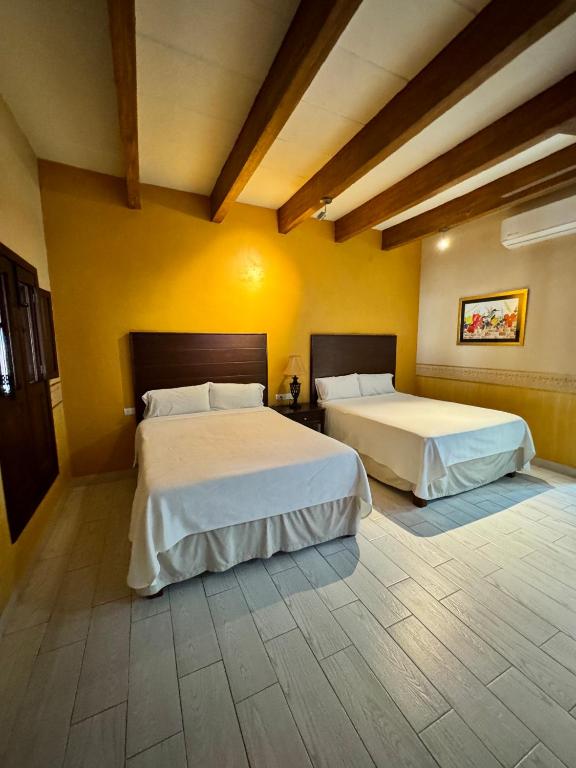 two beds in a room with yellow walls at Hotel Real de los Alamos in Álamos
