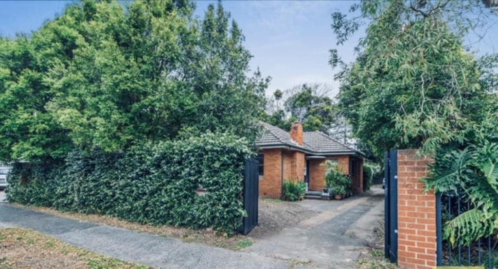 a brick house with a fence and trees at Ocean Breeze Cottage in Umina