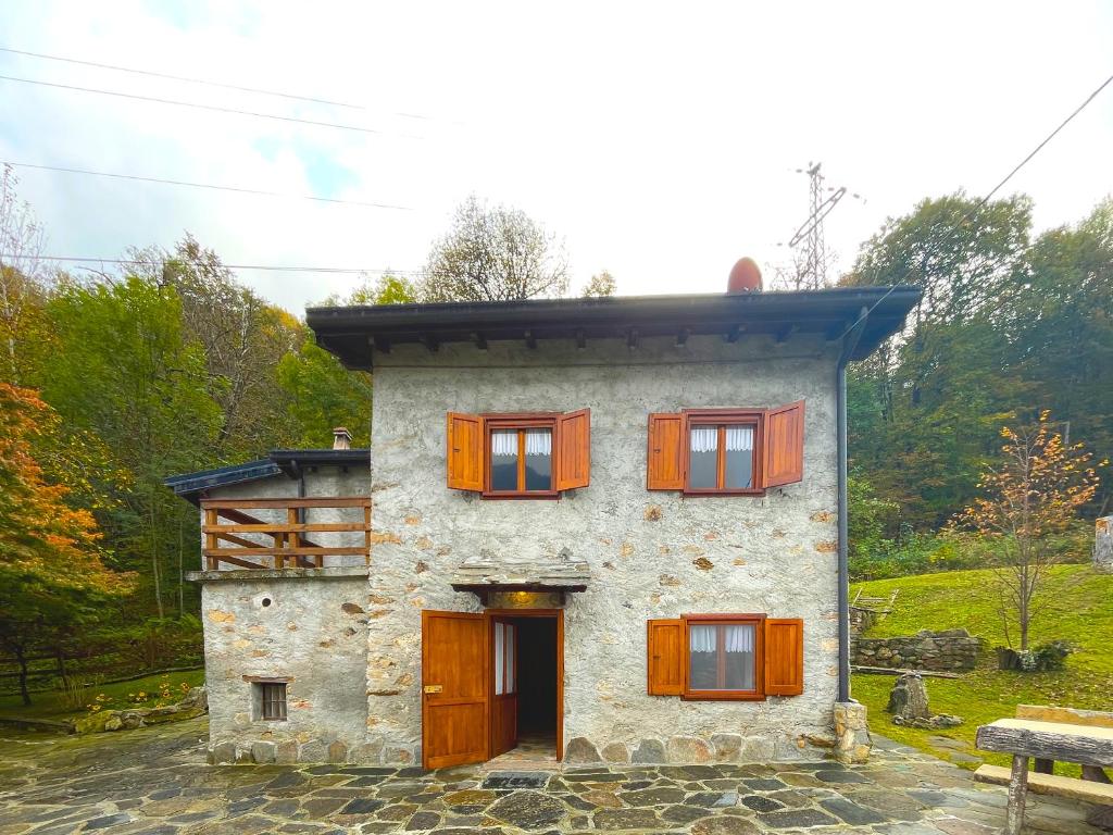 ein Steinhaus mit Holzfenstern im Obergeschoss in der Unterkunft Chalet Casargo in Casargo