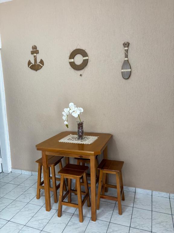 a wooden table with chairs and a vase of flowers on it at Apartamento Boqueirão Ilha Comprida Tati Ortega in Ilha Comprida
