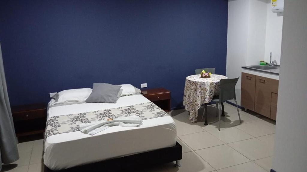 a room with two beds and a table and a table and a kitchen at Apartaestudio con cocina dentro centro comercial in Cartago
