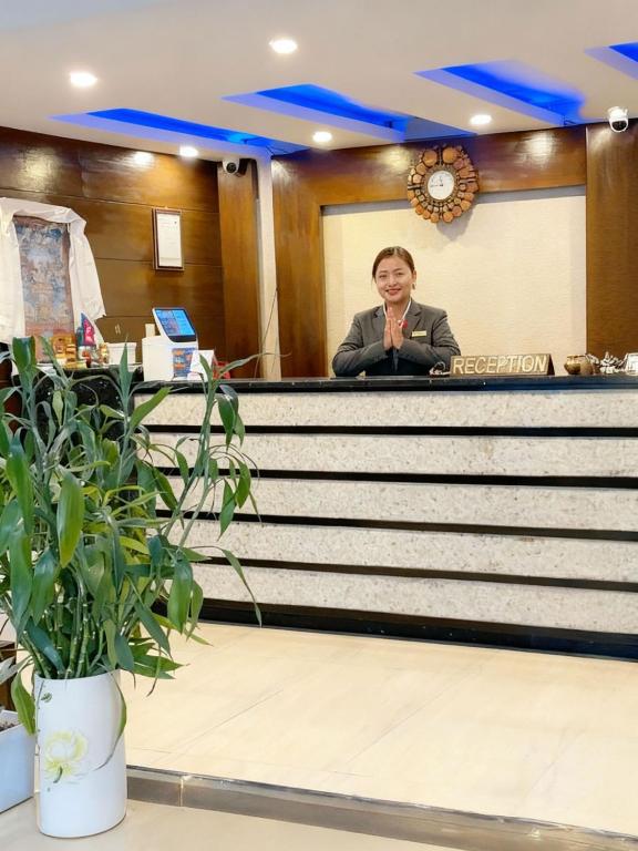a man is sitting at a reception desk at Hotel Tenki Kathmandu in Kathmandu