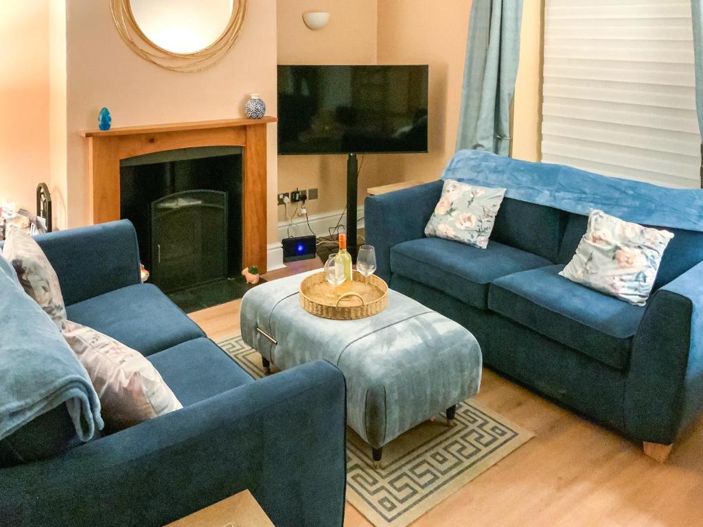 a living room with two blue couches and a fireplace at Paddy's Cottage in Flookburgh