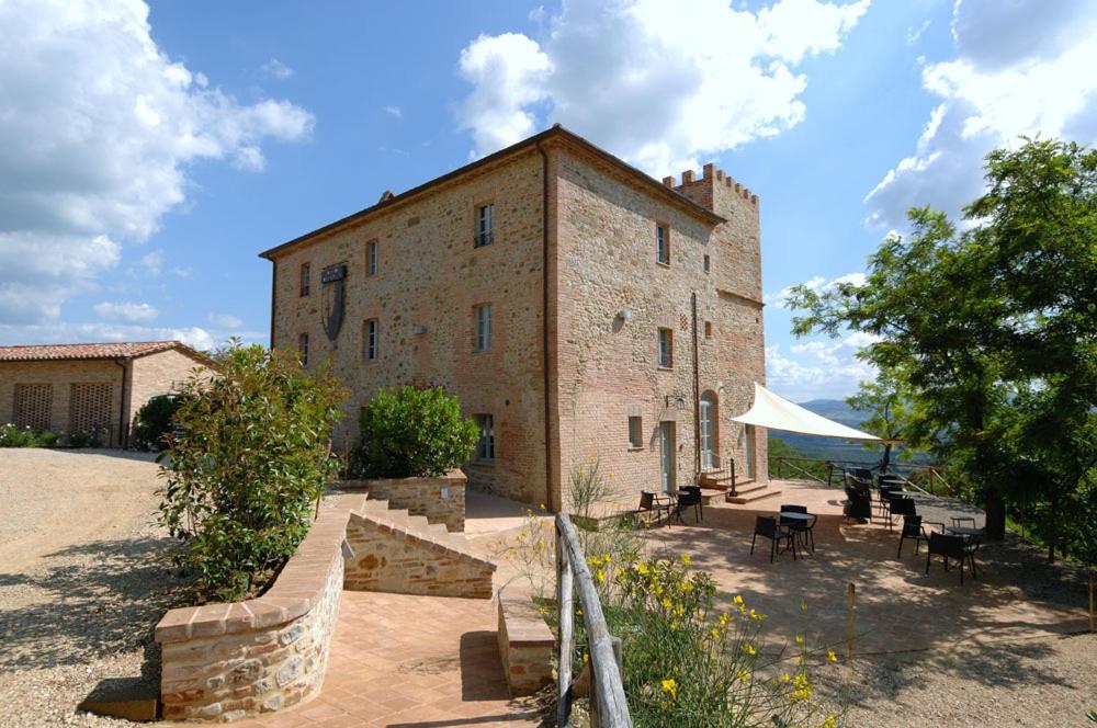 um grande edifício de tijolos com mesas e cadeiras em frente em Locanda Della Picca em Città della Pieve