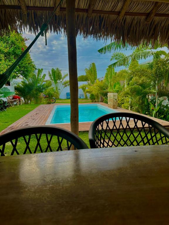 a table with two chairs and a swimming pool at Morada do Vento in Guriú