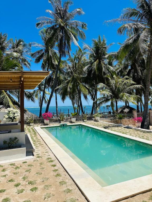 a pool with palm trees and the ocean in the background at Twin Palms Rote in Nembrala