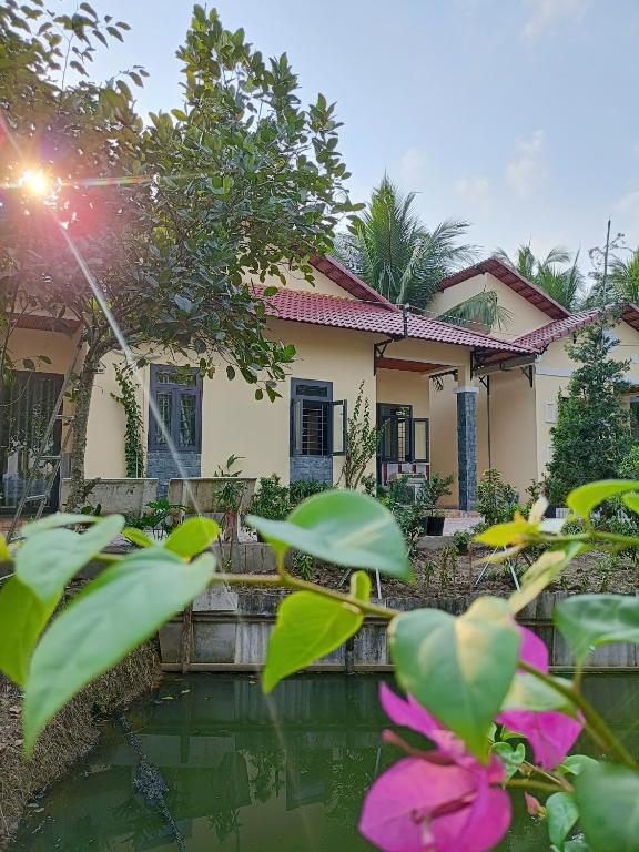 a house with a pond in front of it at Tổ Nhím Homestay in Ấp Cái Chuối