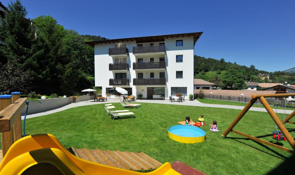 un gruppo di bambini che giocano in un parco giochi di fronte a un edificio di Suvendes Apartments a Prato allo Stelvio