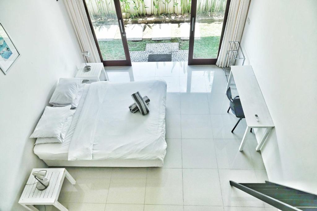 Dieses weiße Zimmer verfügt über ein Bett und einen Schreibtisch. in der Unterkunft Canggu Beach Inn in Canggu