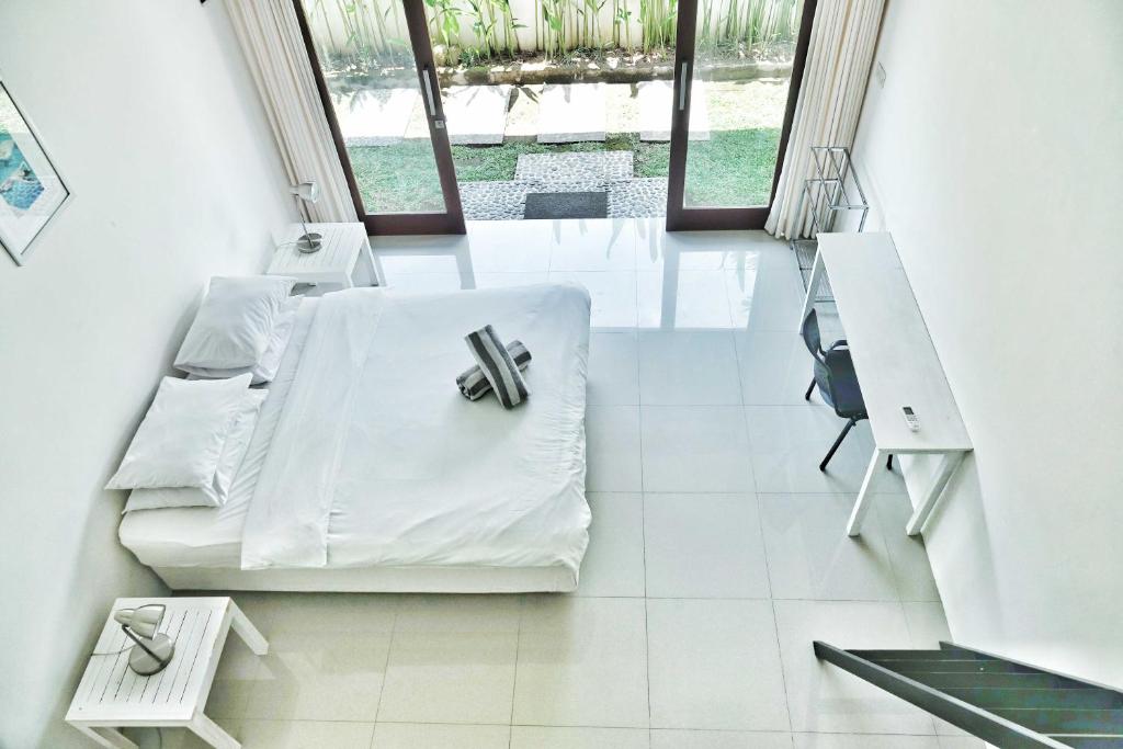 een witte kamer met een bed en een bureau bij Canggu Beach Inn in Canggu