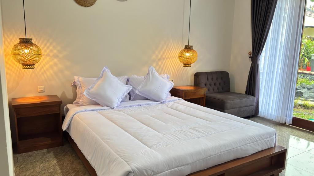 a bedroom with a white bed and a chair at Villa Bumi Detani in Selabintana