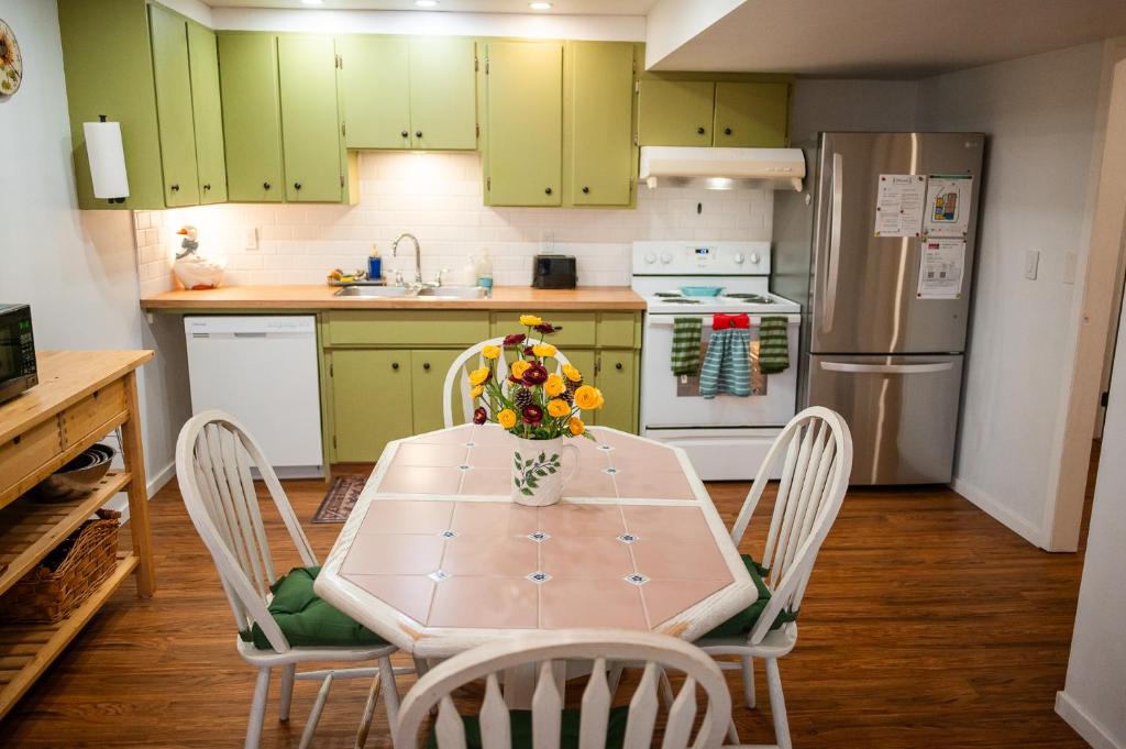 a kitchen with green cabinets and a table and chairs at Spacious 2-Bedroom Basement Suite in Whitehorn, Close to Calgary Airport, Hospital, & Train in Calgary