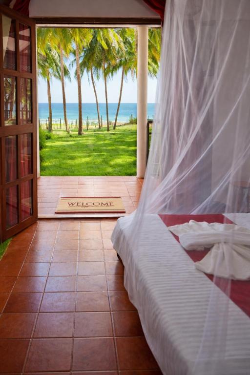 a bedroom with a bed and a view of the ocean at Helios Beach Resort in Tangalle