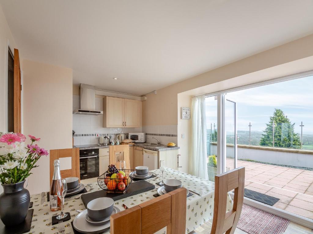 a kitchen with a table and a large sliding glass door at Bwthyn Hudol - Uk46711 in Pwllheli