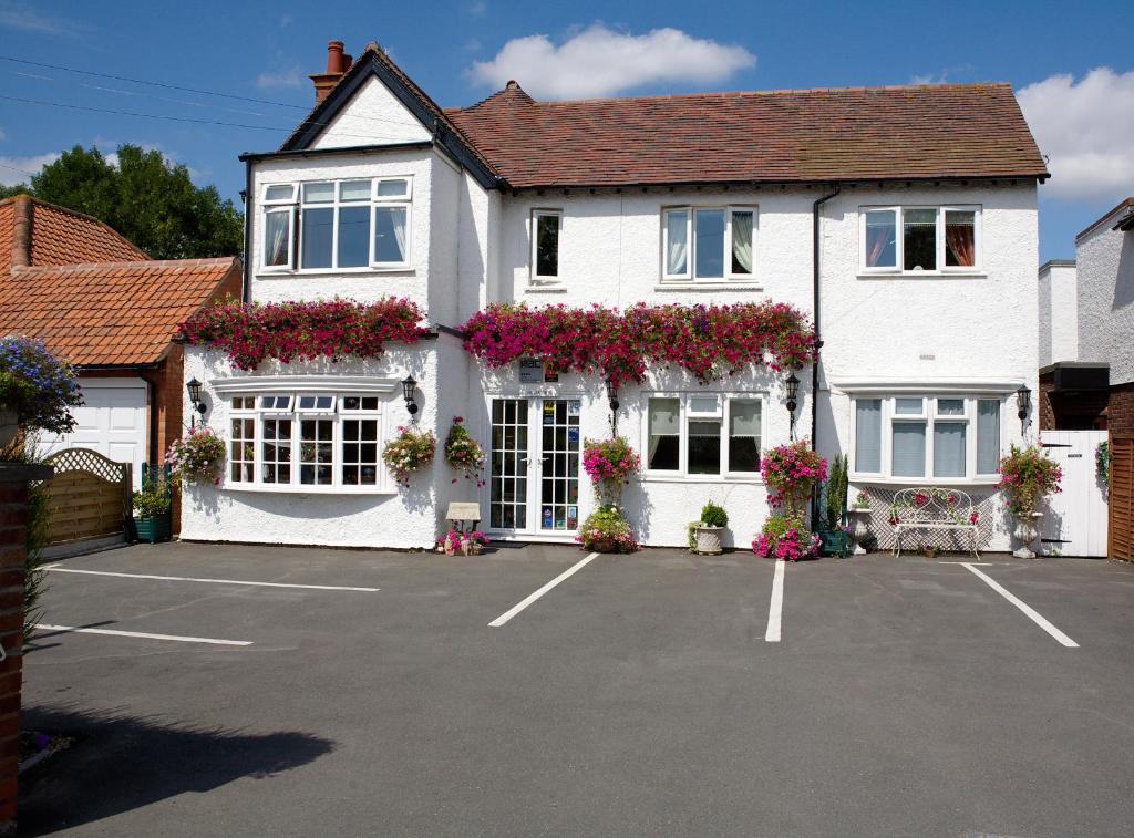 a white house with lots of flowers in a parking lot at Moonraker House in Stratford-upon-Avon