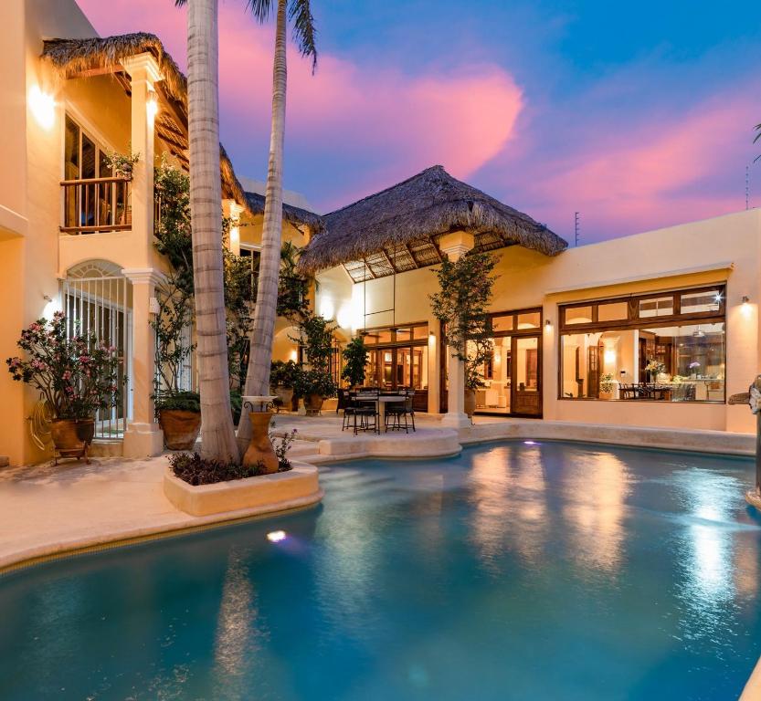a swimming pool in front of a house with palm trees at Villa de Dos Armadillos in Santa Maria Huatulco