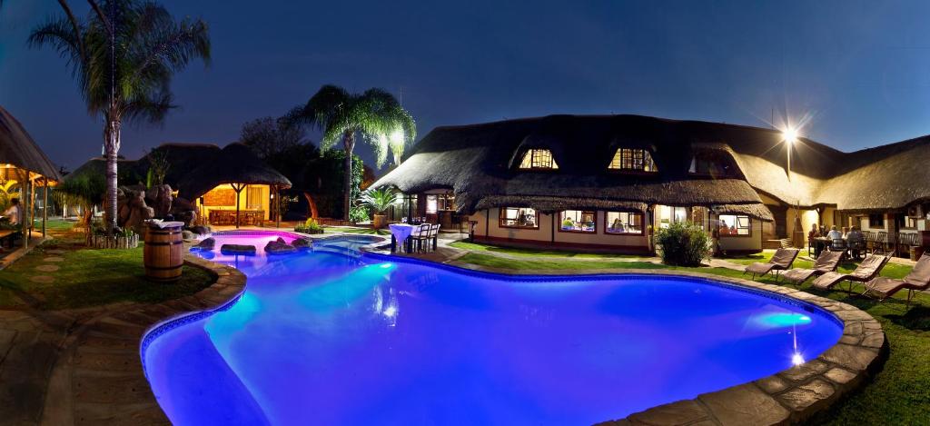 a large blue swimming pool in front of a house at Cest Si Bon Hotel in Otjiwarongo
