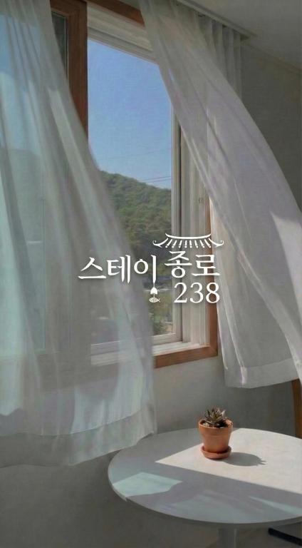 a window with a white curtain and a potted plant at Stay jongno238 in Seoul