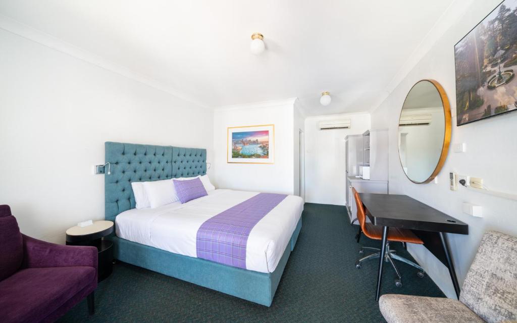 a hotel room with a bed and a mirror at Ben Chifley Motor Inn in Bathurst