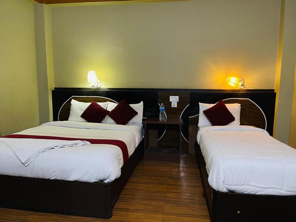 a hotel room with two beds and a table at Hotel Royal Swiss in Sauraha