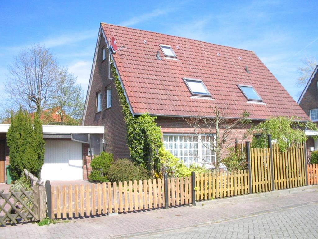a house with a fence and a red roof at up ` Achterdeck in Dornum