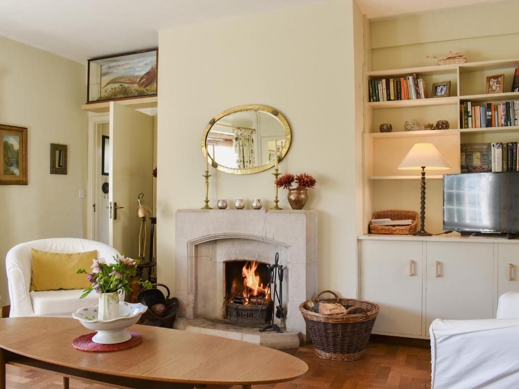 a living room with a fireplace and a table at Coachmans Close in Milverton