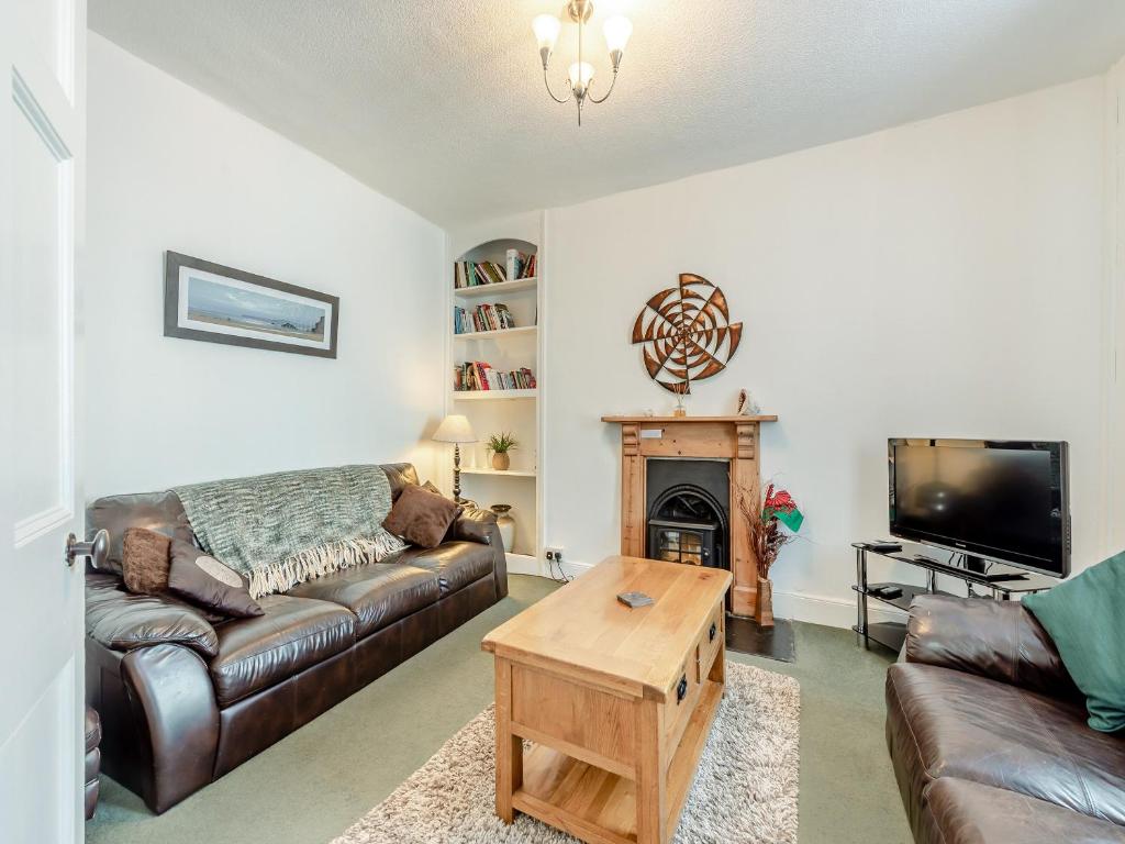 a living room with a leather couch and a tv at Glendower in Aberaeron