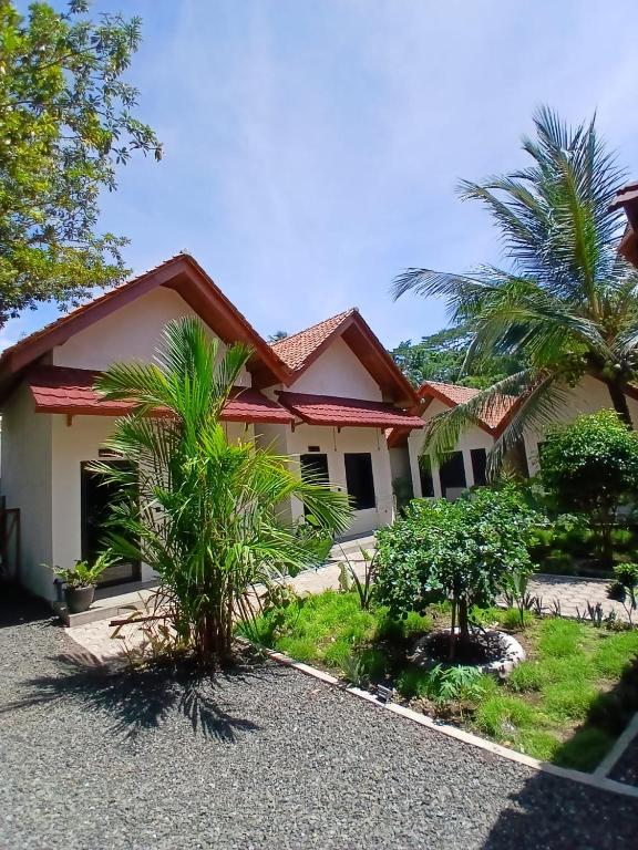 a house with palm trees in front of it at Mini Village in Batukaras