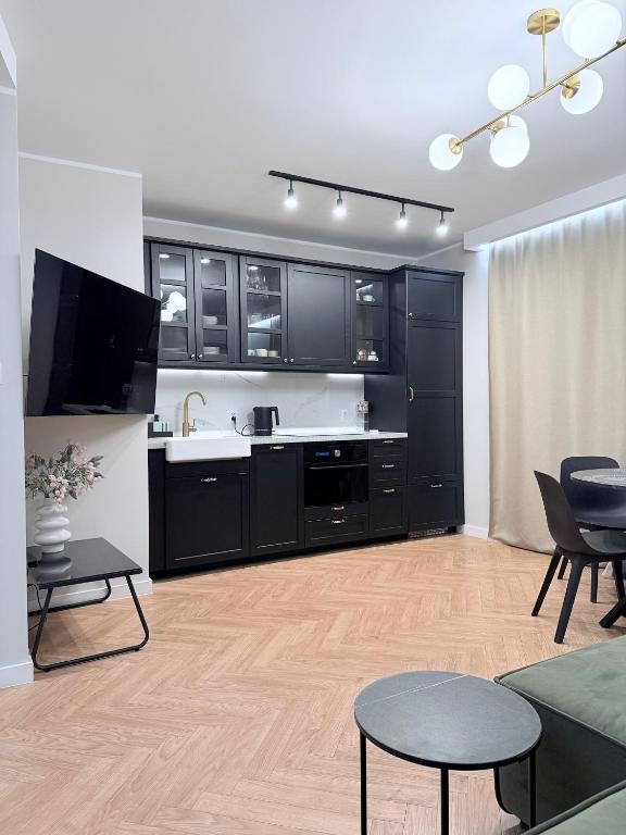 a kitchen with black cabinets and a living room at Kapitańska Przystań - basen & sauna & jacuzzi & klimatyzacja & garaż in Dziwnów