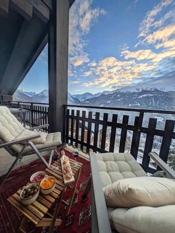 a balcony with a table and chairs and a view of the mountains at Cocon Alpin: Vue Imprenable, Central & Calme in Saint-Luc