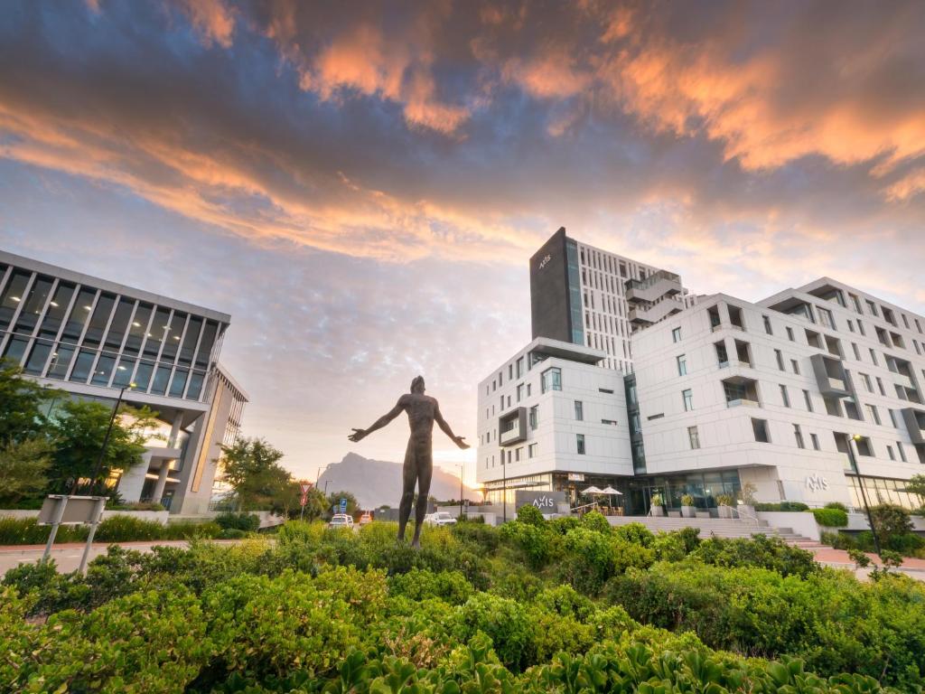 a statue of a man in front of two buildings at Axis Luxury Apartments by Century City Hotels in Cape Town