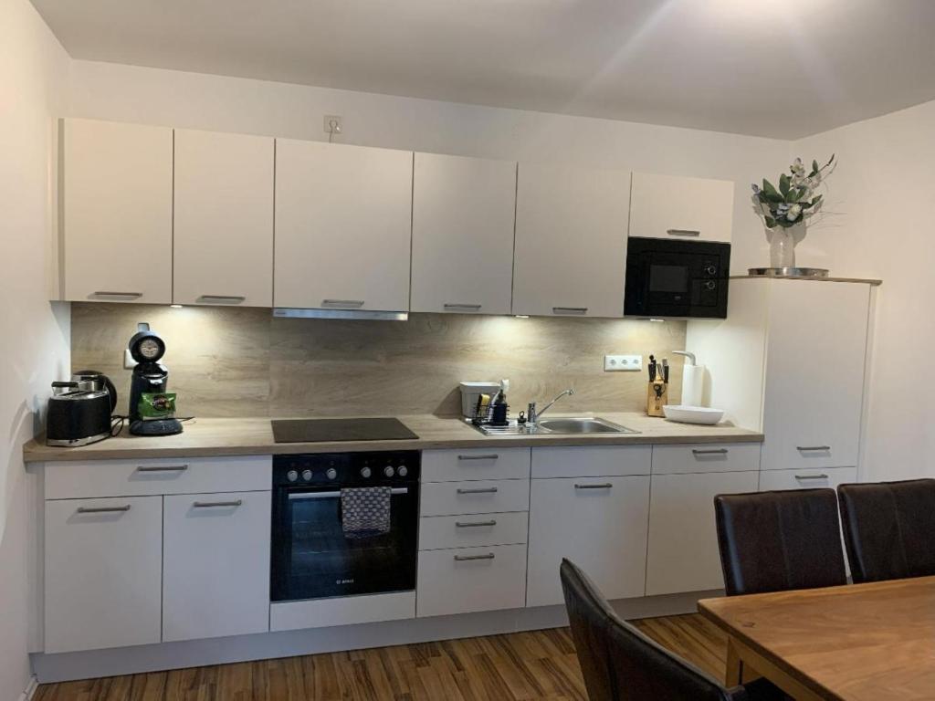 a kitchen with white cabinets and a sink and a table at FeWo Landblick in Hemau